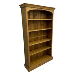 Pine open bookcase, projecting moulded cornice over arched frieze, fitted with four adjustable shelves, on plinth base