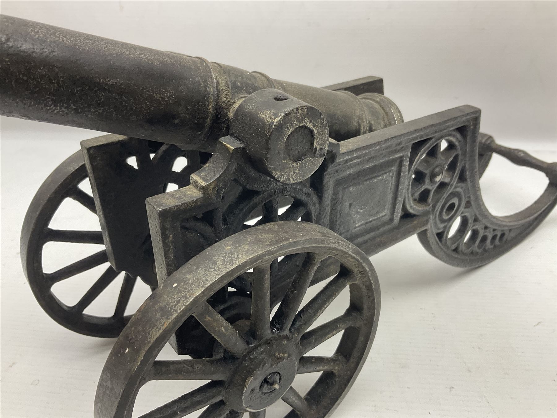 Victorian cast-iron and steel signal cannon, approximately half-inch bore, with 23cm ringed barrel and cylindrical trunnions, on a cast iron carriage with two twelve-spoked wheels and guilloche pierced swept back support, L43cm overall