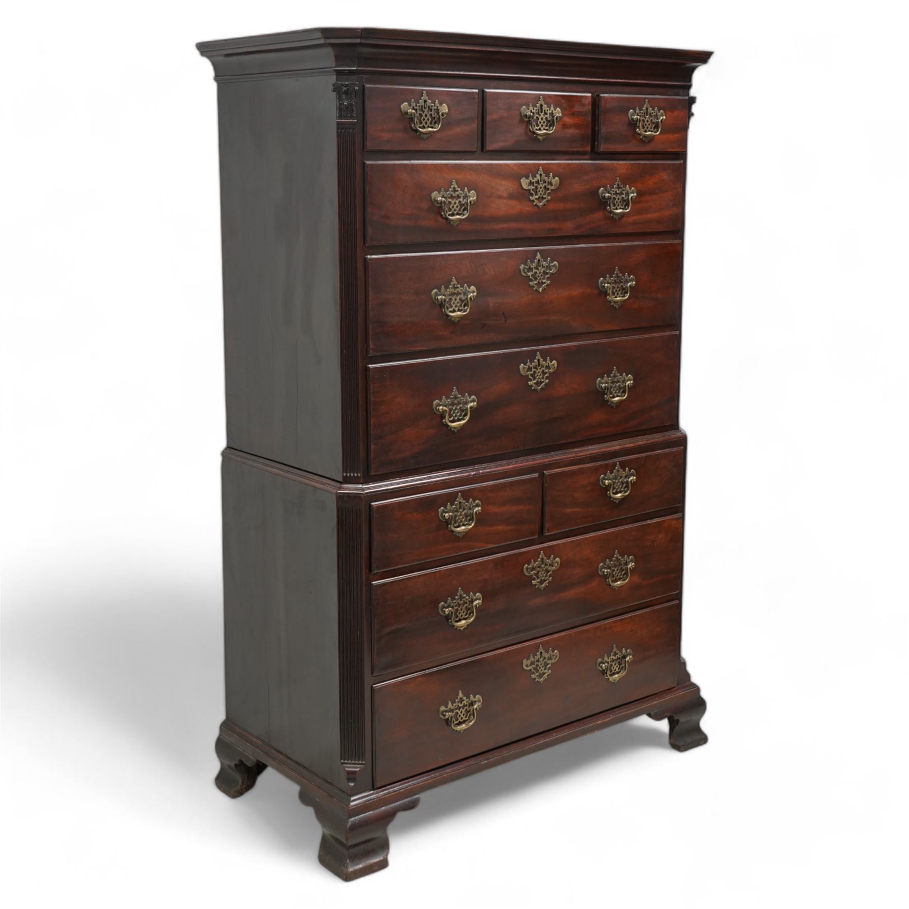 George III mahogany chest-on-chest, canted rectangular form, stepped cavetto moulded cornice, the upper section fitted with three short over three long drawers, the lower section fitted with two short over two long drawers, moulded drawer fronts with shaped and pierced handles plates and swan neck handles, enclosed by fluted corners with acanthus leaf capitals, on ogee bracket feet