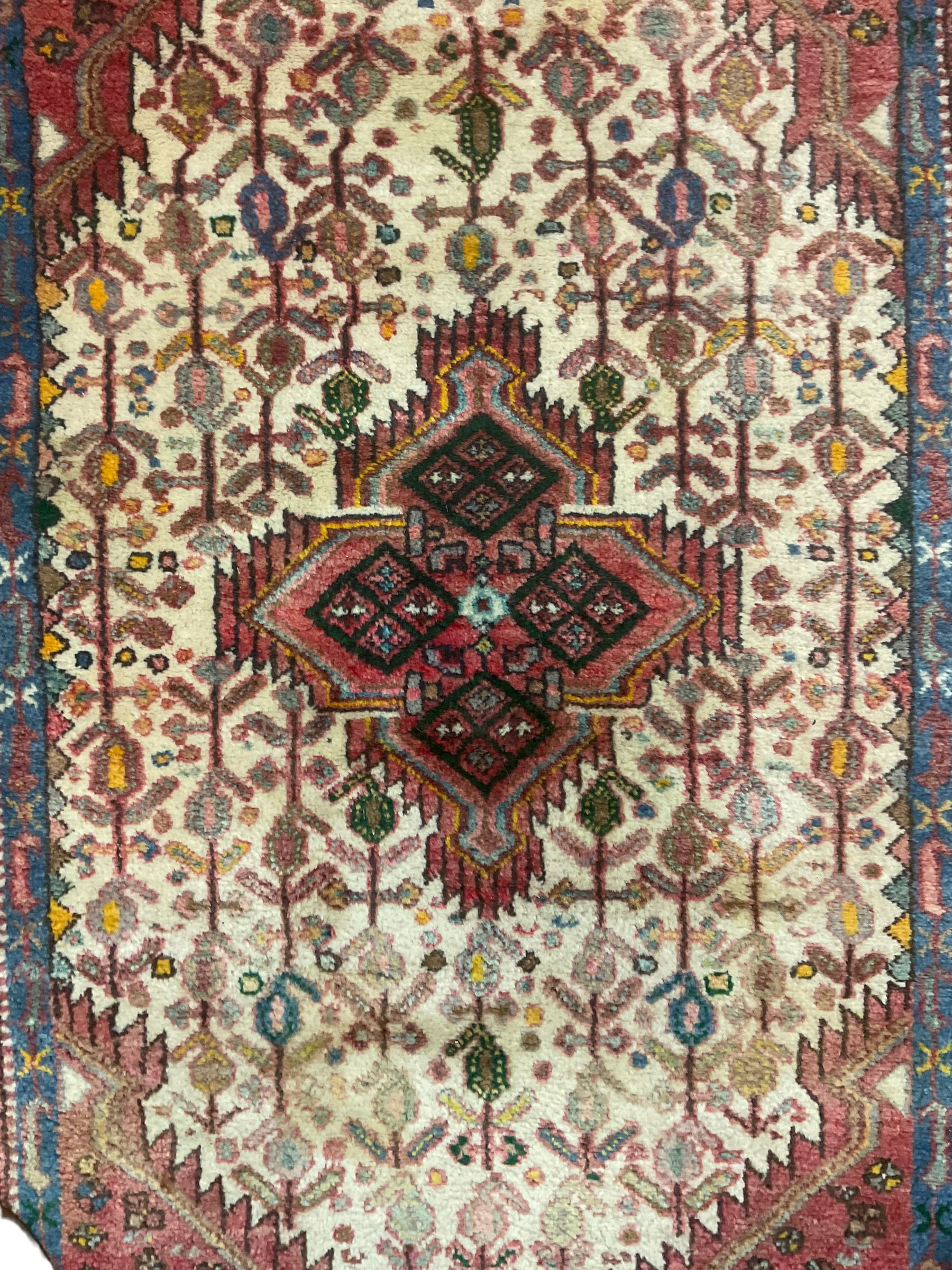 Small Persian rug, ivory and pale red ground, decorated with central medallion within a field of trailing Boteh motifs, geometric design guarded border