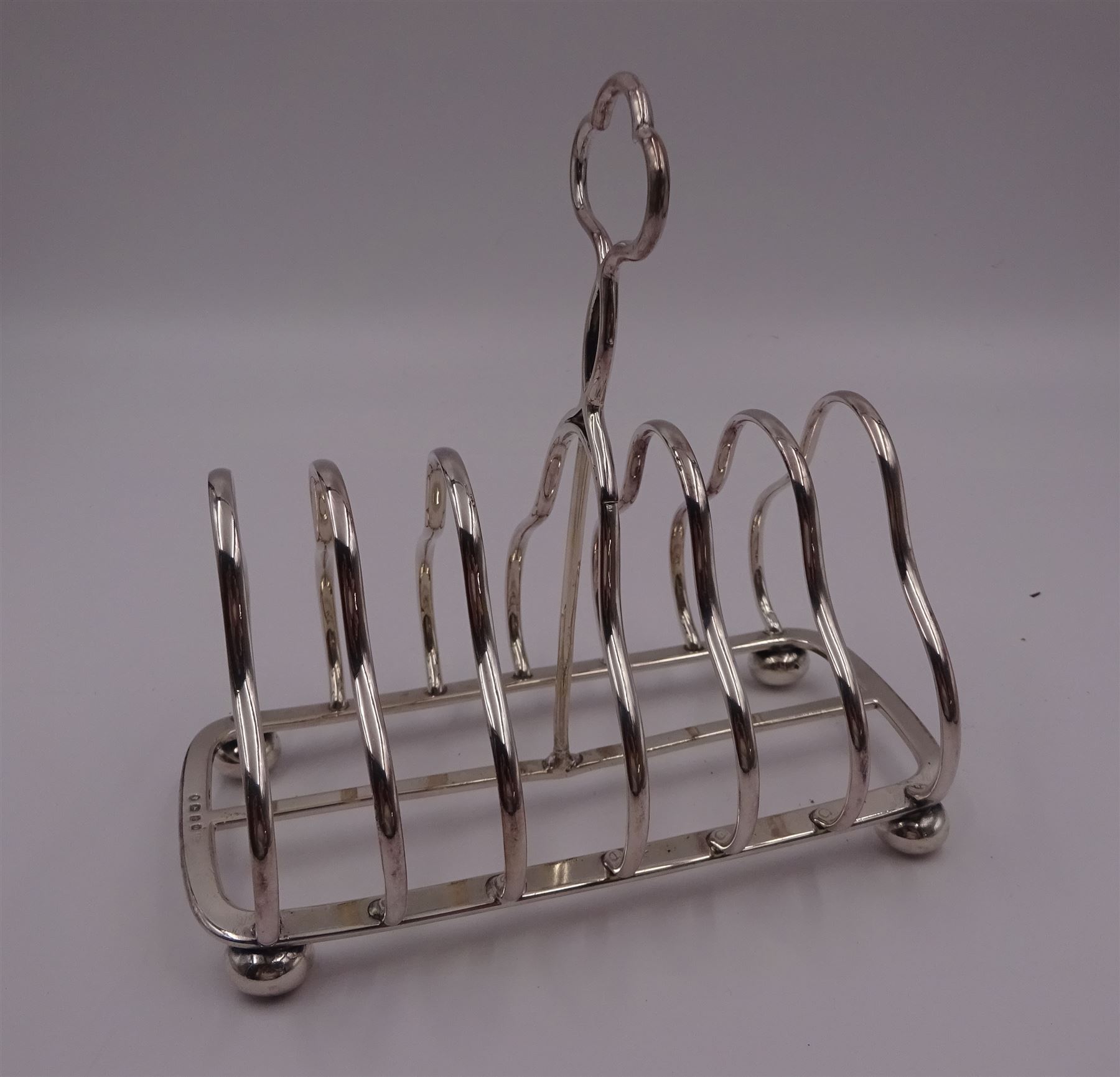 Victorian silver seven bar toast rack, each bar of trilobed form, with similar loop handle and upon four bun feet, hallmarked John Gilbert, Birmingham 1863, H16.5cm