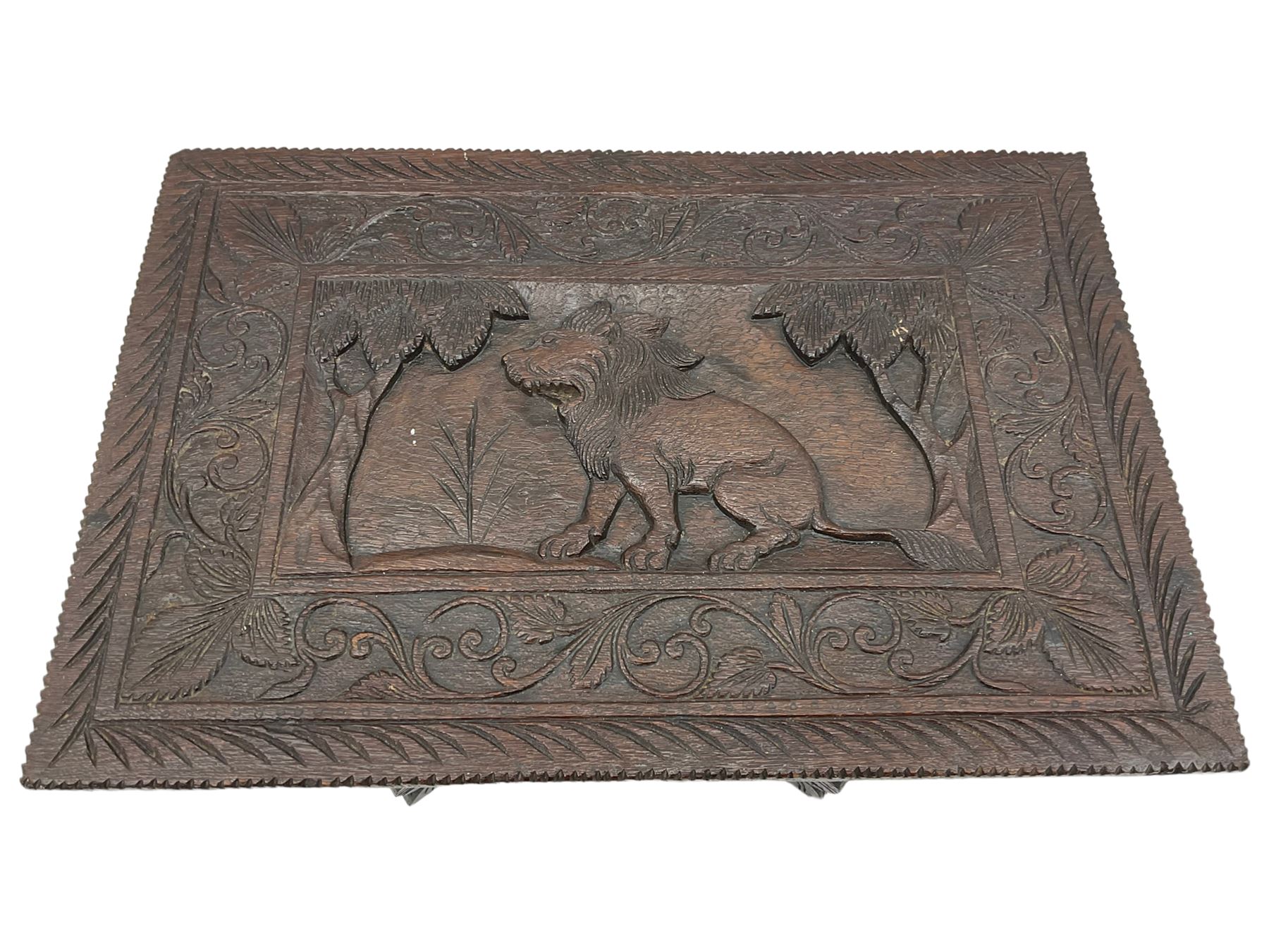 Early 20th century Anglo-Indian heavily carved hardwood table, the rectangular top carved with lion amongst trees, scrolling branch and foliage border, on leaf carved and pierced supports united by undertier 