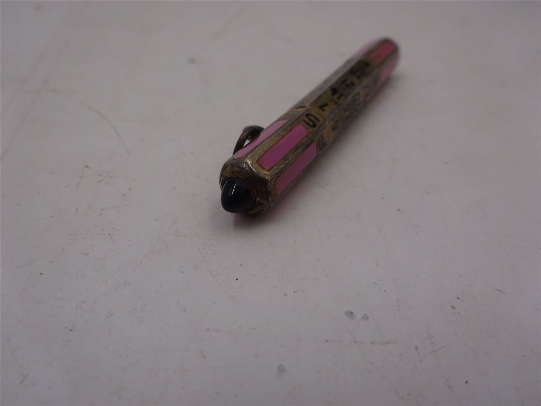 1920s silver and enamel calendar pencil, the silver faceted body decorated with panels of pink enamel with central adjustable calendar to centre, set with purple polished stone to one end, with London import marks for 1927, Cohen & Charles, L6.5cm