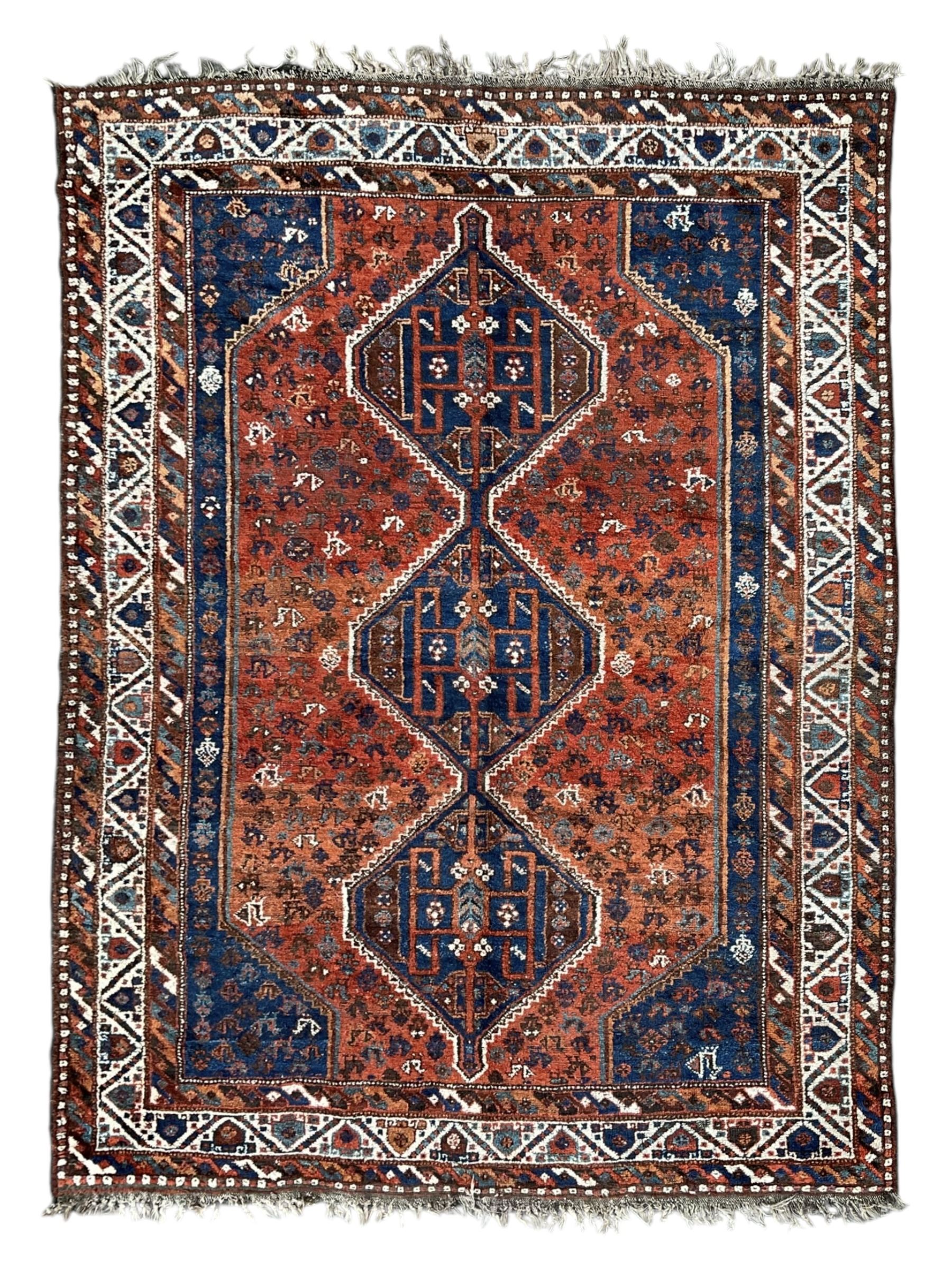 Persian Shiraz crimson ground rug, three connected lozenge medallions on a field decorated with small bird motifs, the main border decorated with repeating geometric motifs, within hooked guard stripes 