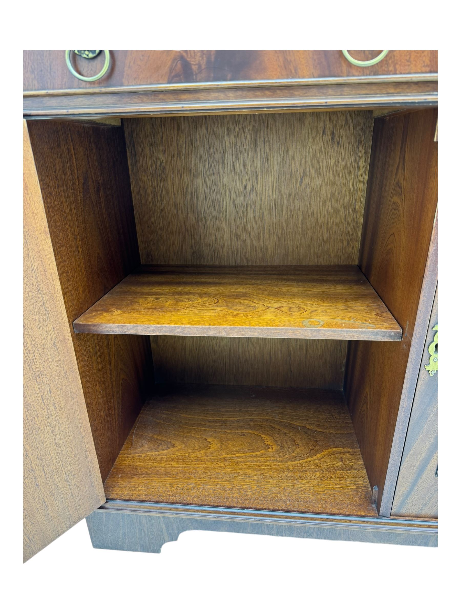 Georgian design mahogany bookcase on cupboard, projecting moulded and dentil cornice, two display cabinets enclosed by glazed doors above over three drawers and three cupboards, on bracket feet