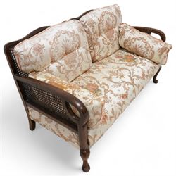 Early 20th century bergere lounge suite - two-seat sofa (W140cm, H80cm, D72cm); and pair of armchairs (W64cm); together with footstool, upholstered in floral fabric