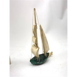 A Japanese carved ivory model of a sailing boat, surmounted by three carved figures (a/f), L22.5cm, together with a smaller sail boat with malachite hull and ivory sails and rudder, H18cm. 