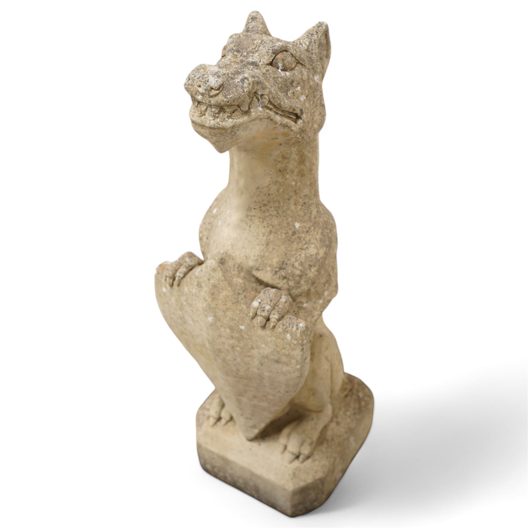 Near pair of cast stone garden seated dragons, snarling jaw holding shield on chamfered base 