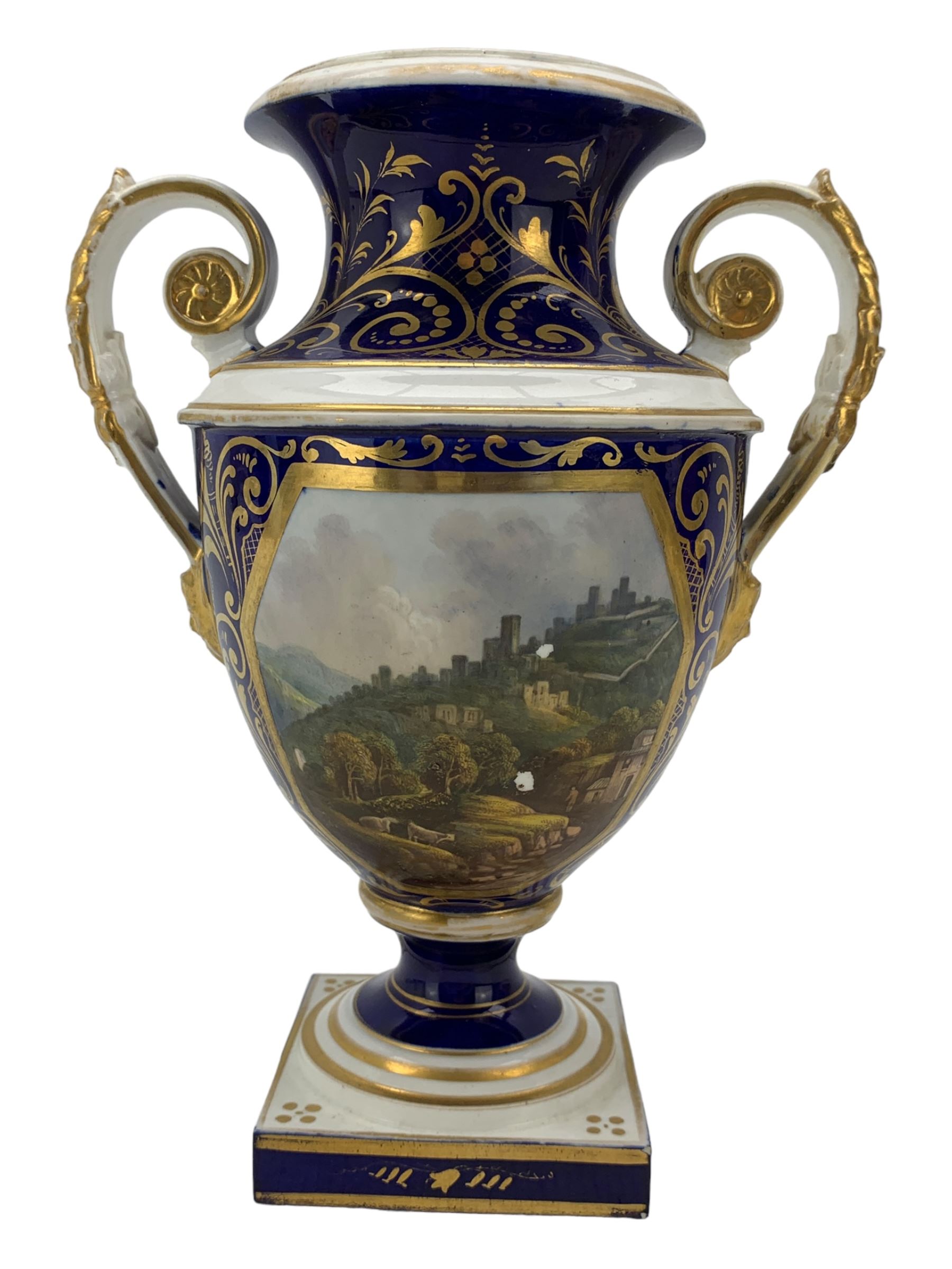 Early 19th century Derby porcelain urn, the reserve painted with a pastoral landscape and castle in the distance, with twin scroll and mask handles, upon a square pedestal base, H23cm, together with a Derby shell-shaped dish, centrally hand painted with a landscape scene titled 'In North Wales', within a cobalt blue and gilt border, L25cm (2)