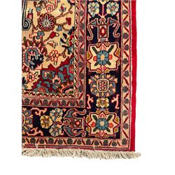 Central Persian Isfahan crimson ground carpet, central floral medallion in ivory and blue, set within a field of dense floral patterns, bordered by a navy band decorated with stylised flower heads and vines