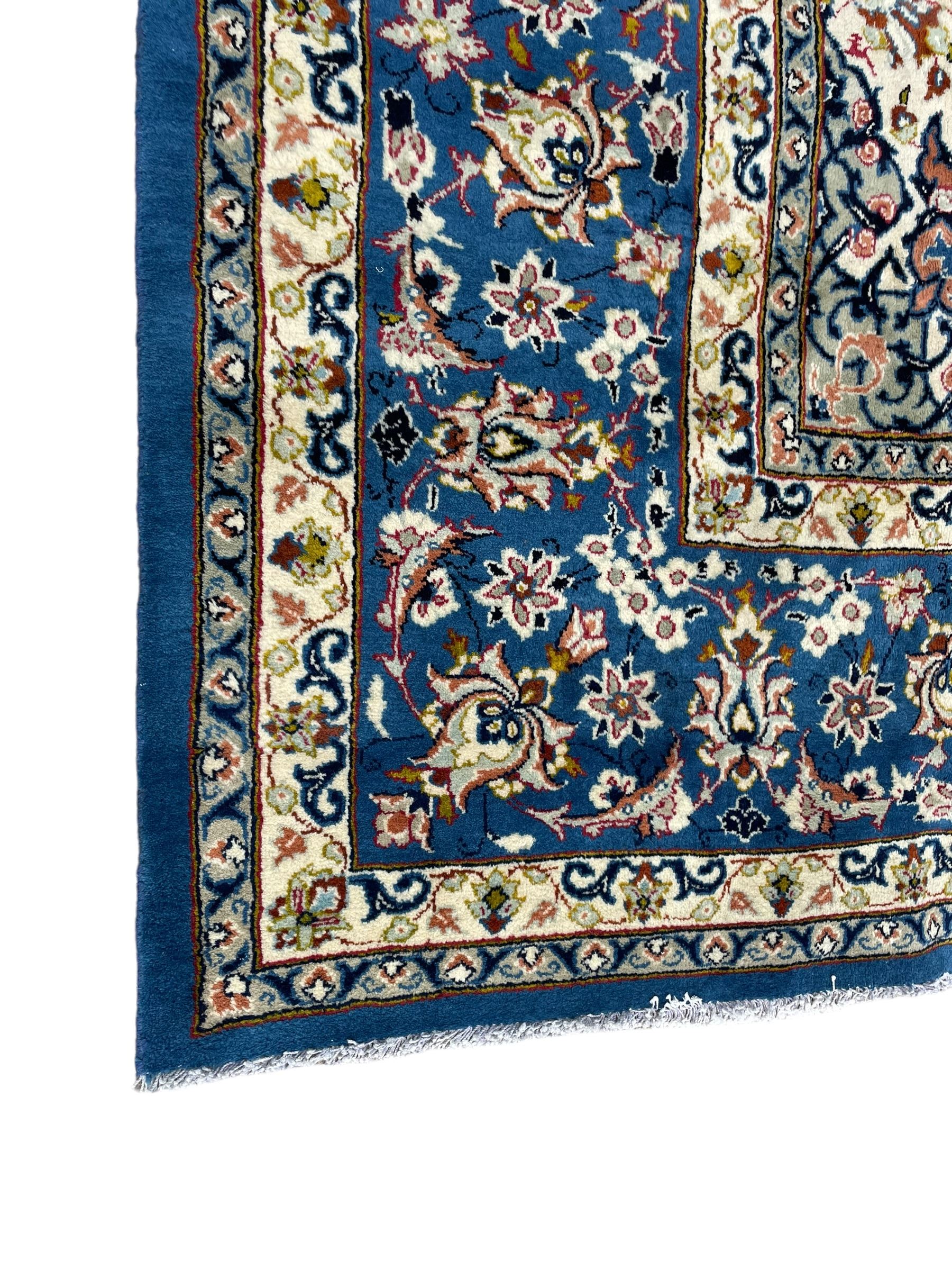 Persian Nain blue ground carpet, overall arabesque design, centre rosette medallion with eight projecting palmettes, the surrounding field decorated with interlacing branches and stylised plant motifs, within floral pale ground spandrels, the guarded border decorated with repeating stylised floral pattern 