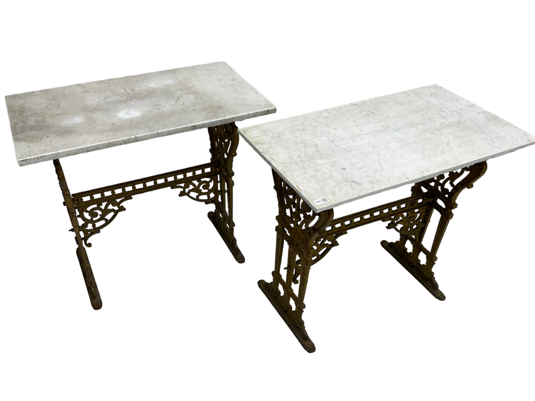 Pair of 19th century cast iron entrance tables, rectangular marble top over ornate gilt bases with scrolling foliate design and sledge feet, united by balustrade stretcher with scroll spandrels