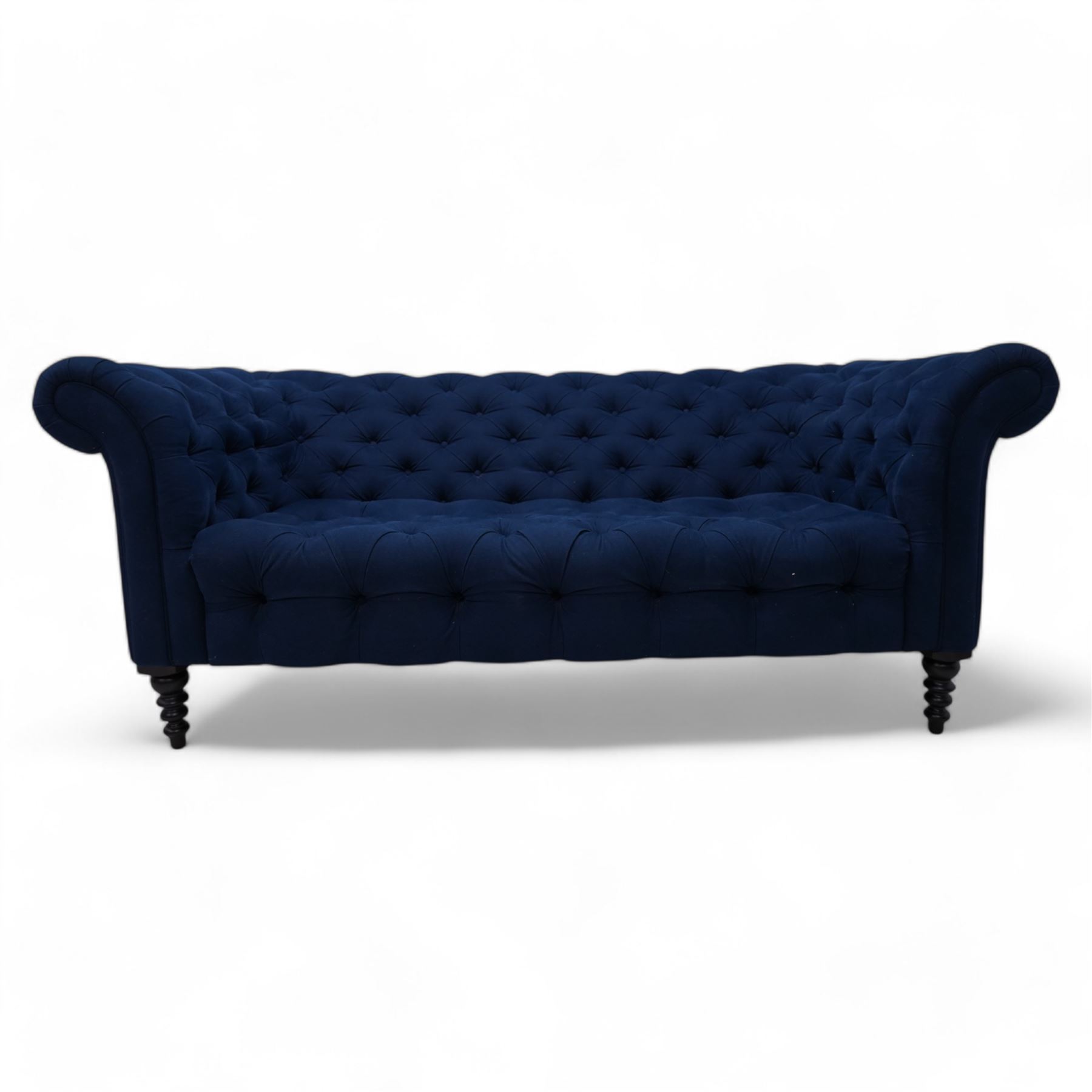 Chesterfield two-seat sofa, traditional shape with rolled arms, upholstered in deep blue buttoned fabric, on black finish turned front feet 