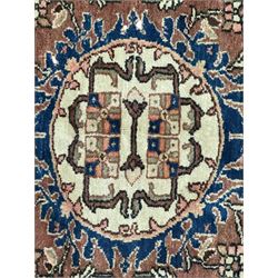 Persian Hamadan ground rug, central medallion design with a salmon pink field, accentuated by navy blue spandrels, surrounded by a stylised floral border in cream and blue tones