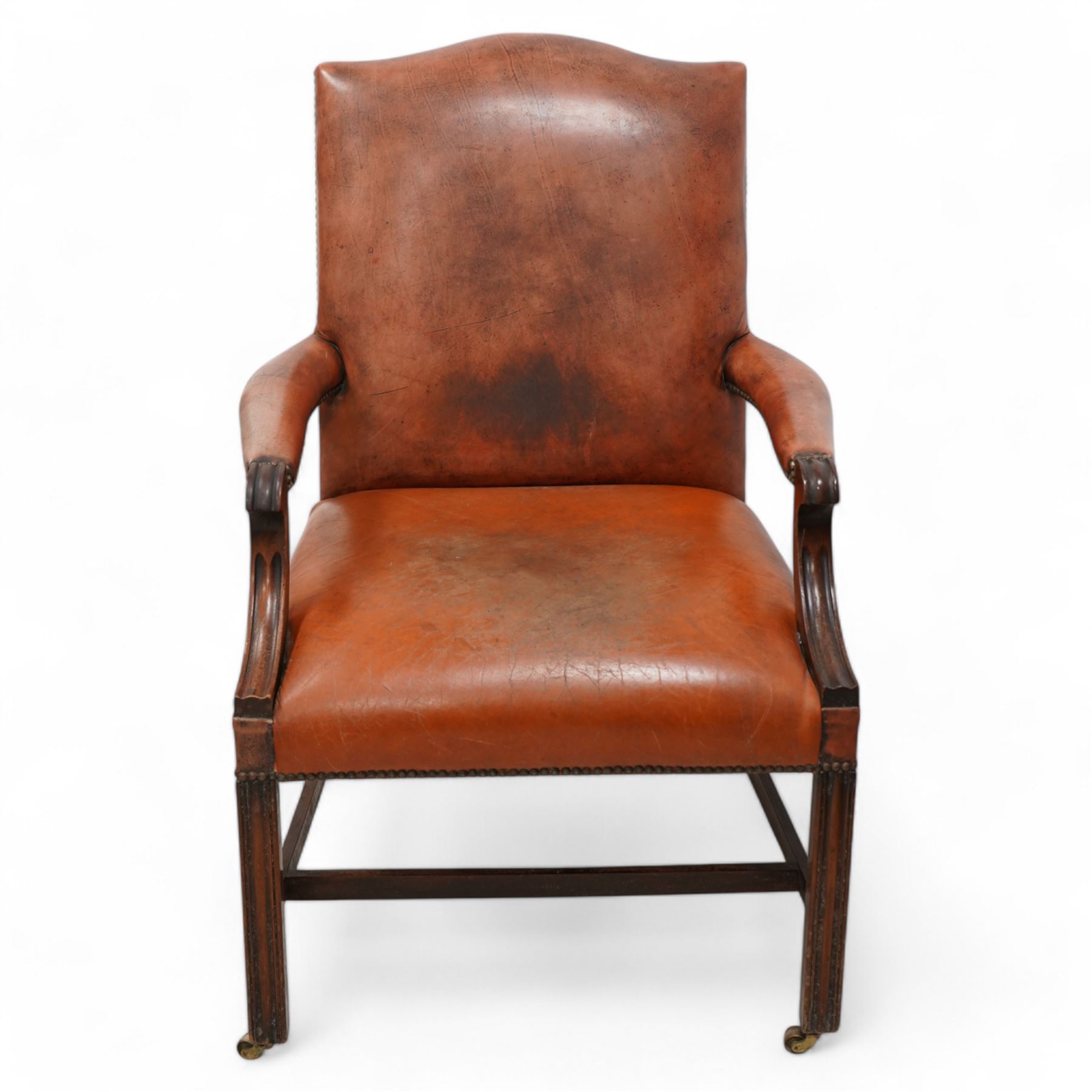 Georgian design Gainsborough elbow chair, upholstered in leather with studwork bands, moulded square supports united by H-stretcher, on brass castors 