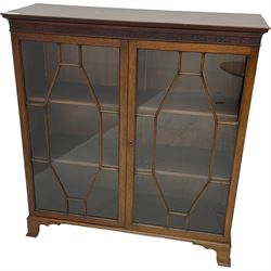 Early 20th century mahogany bookcase, projecting dentil cornice over blind fretwork frieze, enclosed by two astragal glazed doors, on shaped bracket feet 