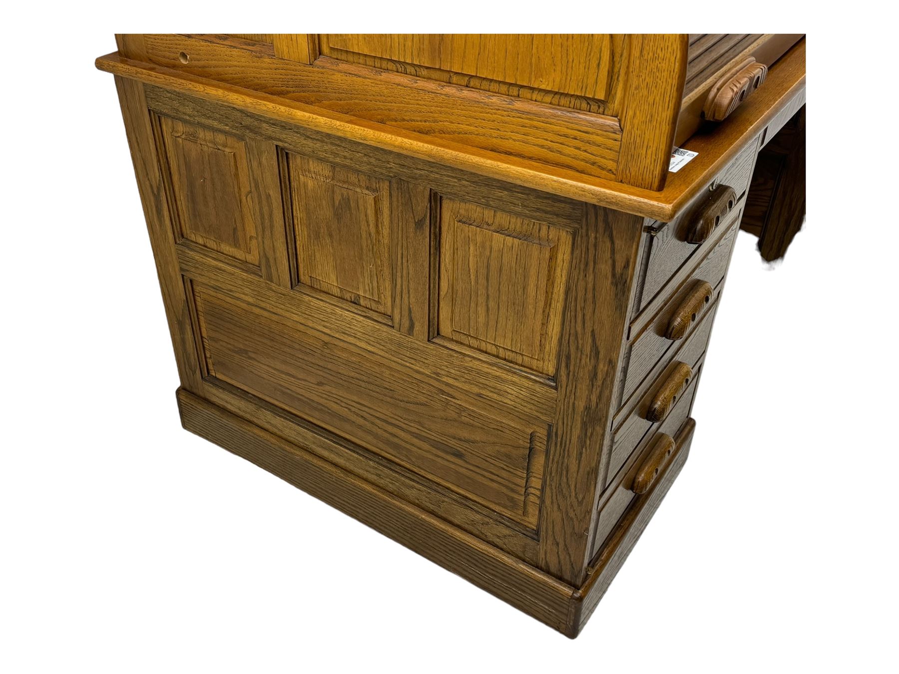 Early 20th century oak tambour roll-top desk, the top with fitted interior including drawers, pigeonholes and compartments, the twin pedestals fitted with four drawers with carved handles, supported by plinth base 