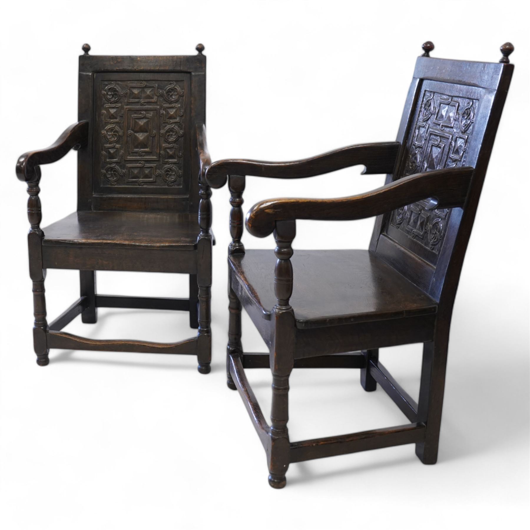 Pair 17th century design wainscot open armchairs, the cresting rail with turned finals over panelled back, the panel carved with geometric pattern and flower heads, shaped arms over plank seat, on turned supports united by stretchers 