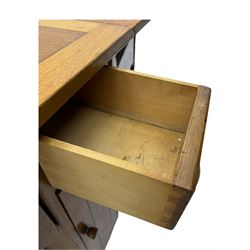 Early 20th century oak drop-leaf table, in the style of Harris Lebus, featuring rectangular top over central pedestal base, with two drawers and two cupboards, on gateleg supports