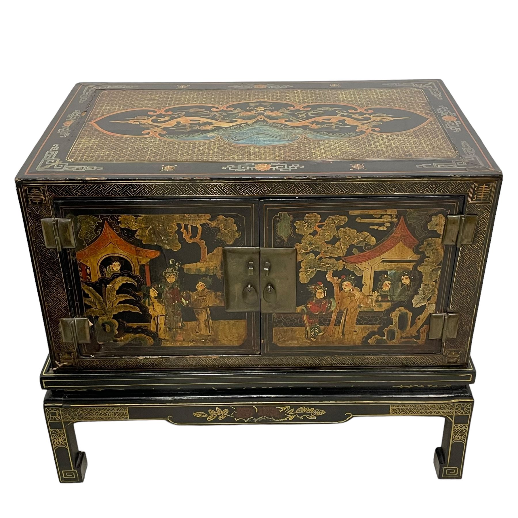 Pair of early 20th century Chinese ebonised and lacquered wood cabinets, the top decorated with dragons over lapping waves within a gilt patterned panel, the surrounding band decorated with Chinese symbols and flowerheads, enclosed by two doors each with village scenes with pagodas, figures and trees, the panelled sides decorated with a figure riding a dragon on stands with gilt decorated 