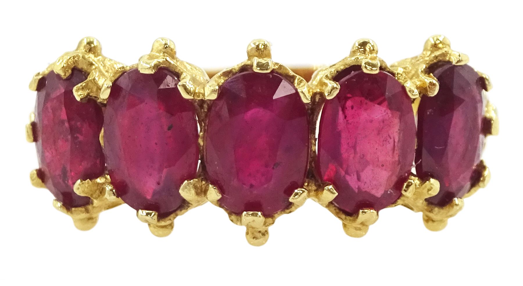 18ct gold five stone oval cut glass-filled ruby ring, with scroll design shoulders, London 2005