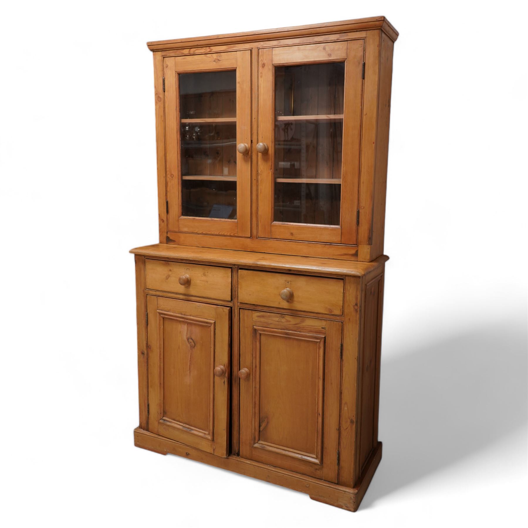 Late 20th century waxed pine dresser, raised display cabinet enclosed by two glazed doors, the base fitted with two drawers over panelled cupboard, on plinth base