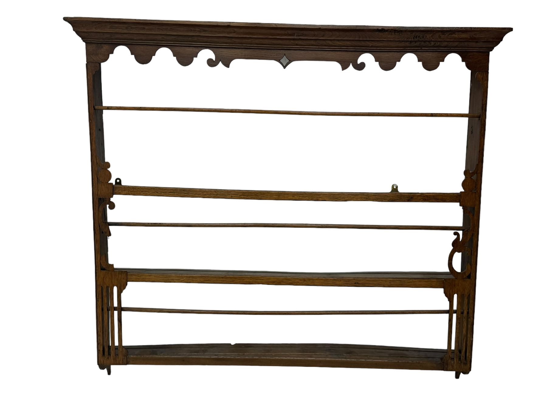 Two Victorian pine plate racks, one with scalloped cornice with central diamond shape and scroll ends over three shelves, the other with scalloped cornice, three shelves and fifteen hooks (2)