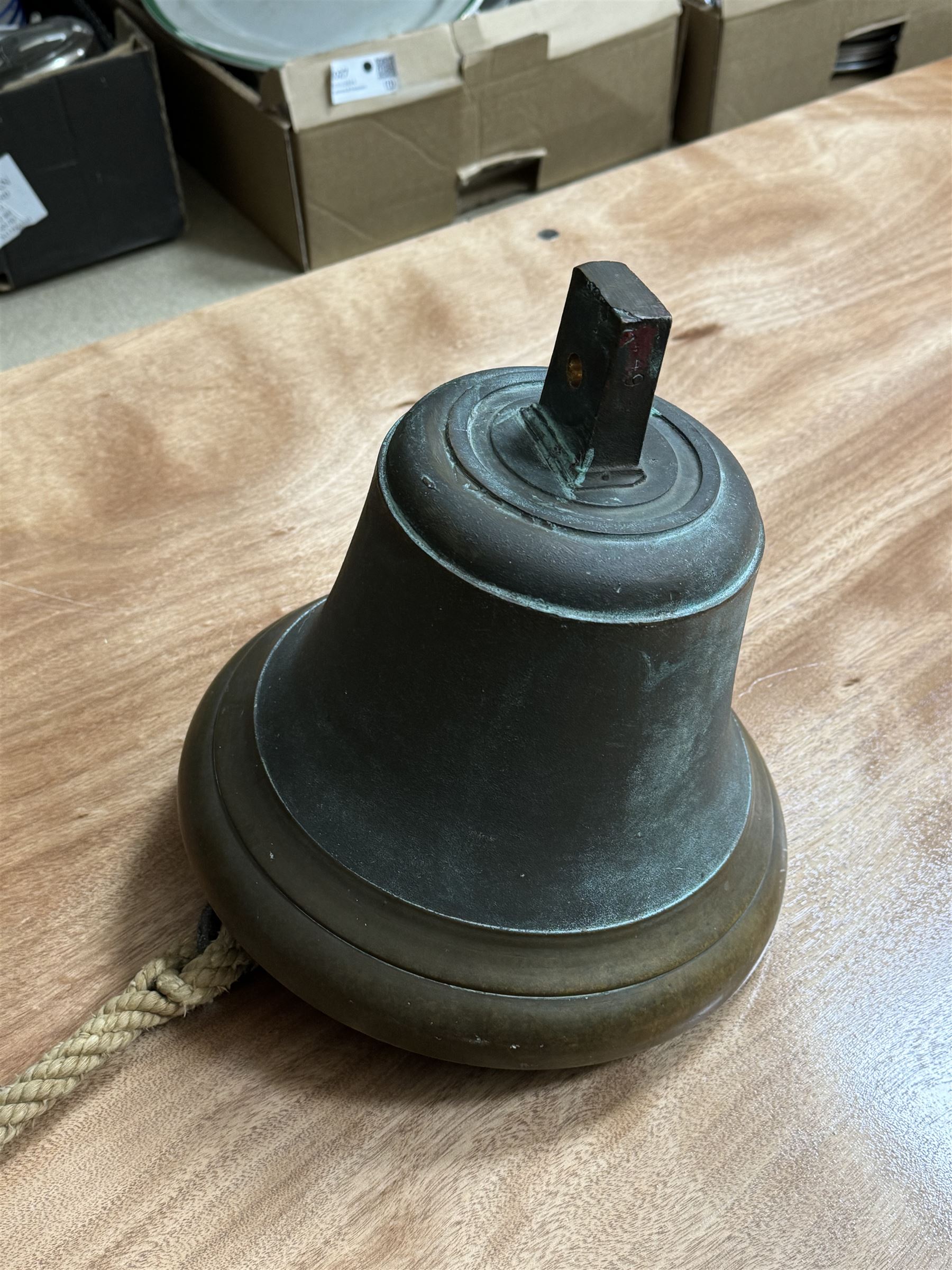 Late 19th century/early 20th century bell with rope pull, probably a fire bell, marked LCC G49 to canon, upon a black painted wrought iron wall mount, bell H29cm, mount H64cm