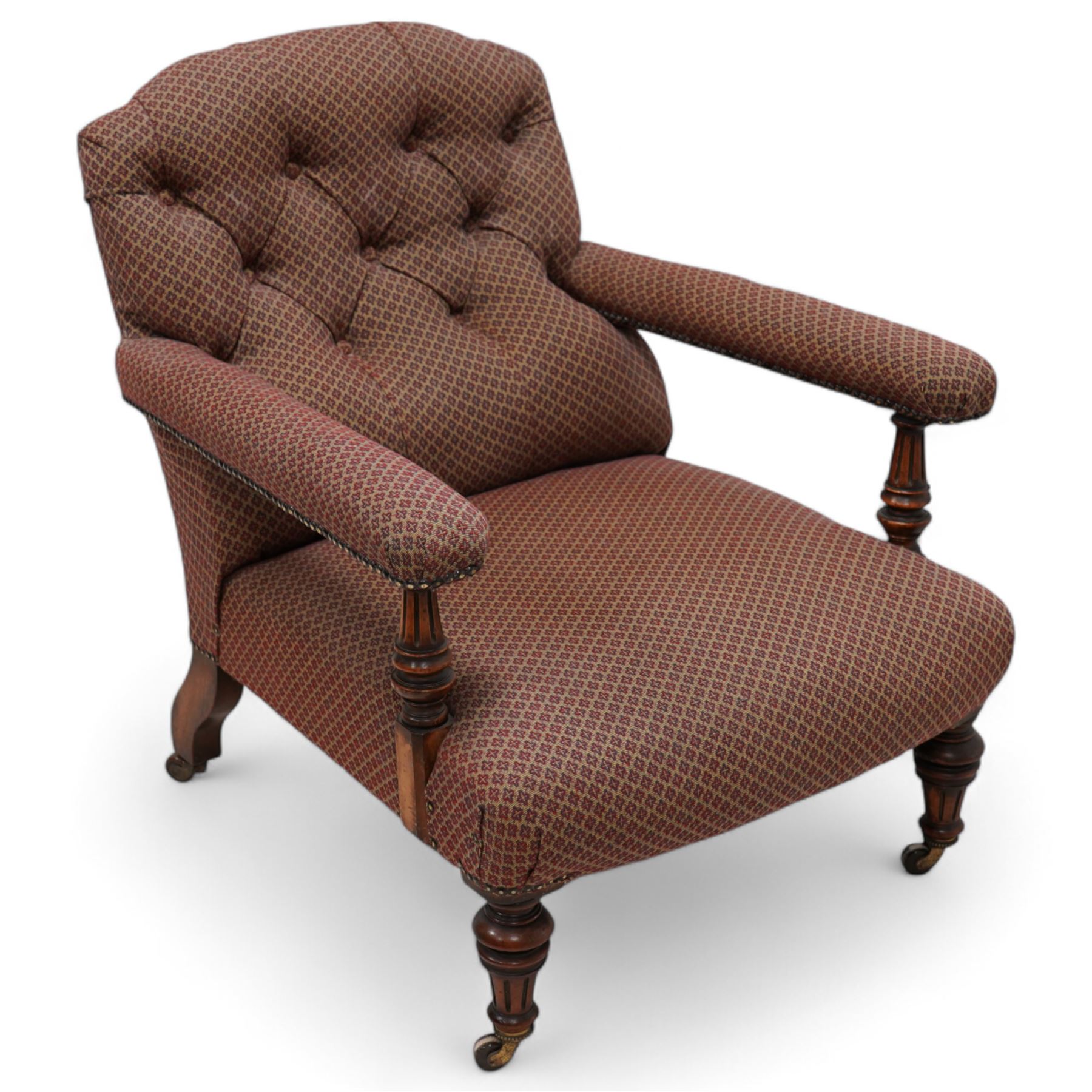 Late 19th century drawing room walnut framed open armchair, arched back over fluted and turned arm terminals and deep sprung seat, upholstered in buttoned maroon patterned fabric with stud detail on turned and fluted supports with castors