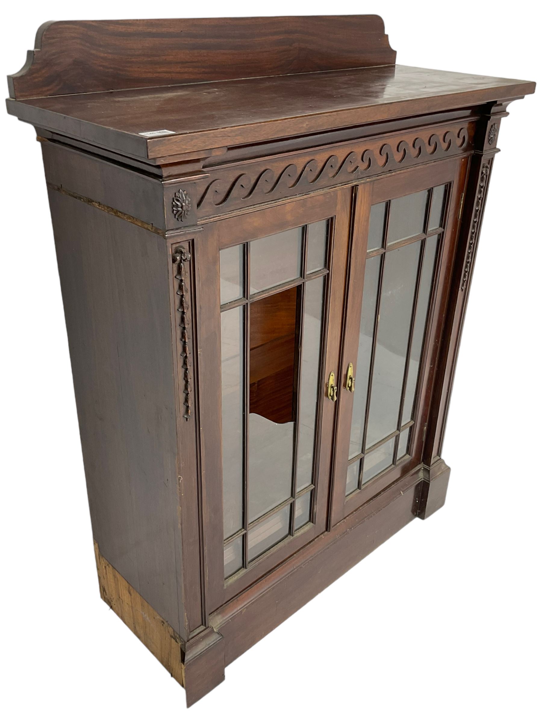 19th century mahogany display cabinet, rectangular top over frieze decorated with Vitruvian scroll mount, enclosed by two astragal glazed doors, the upright rails decorated with trailing bellflowers, on moulded plinth