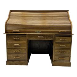 Early 20th century oak tambour roll-top desk, the top with fitted interior including drawers, pigeonholes and compartments, the twin pedestals fitted with four drawers with carved handles, supported by plinth base 