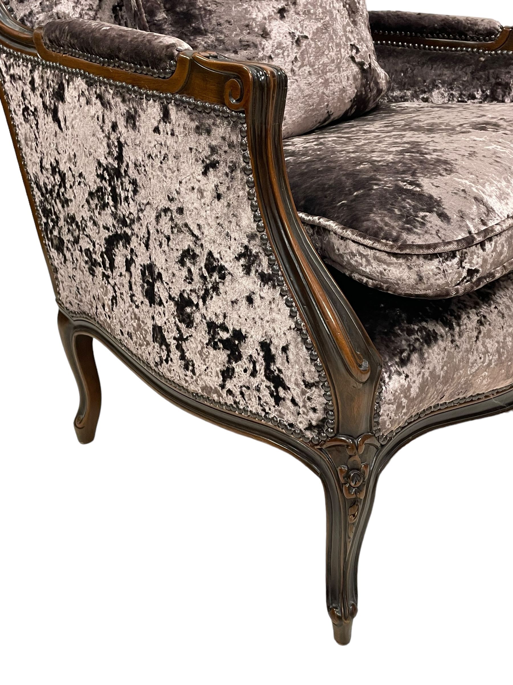 French design walnut framed wide-seat armchair, moulded frame carved with flowers, upholstered in purple crushed velvet, the lower rail carved with flowers and extending foliage, on cabriole feet