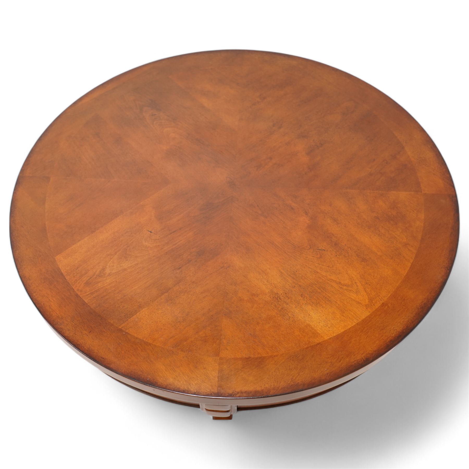 French cherry wood circular coffee table, segment veneered top with crossbanding over plain frieze, curved supports united by magazine under-tier, on spade feet