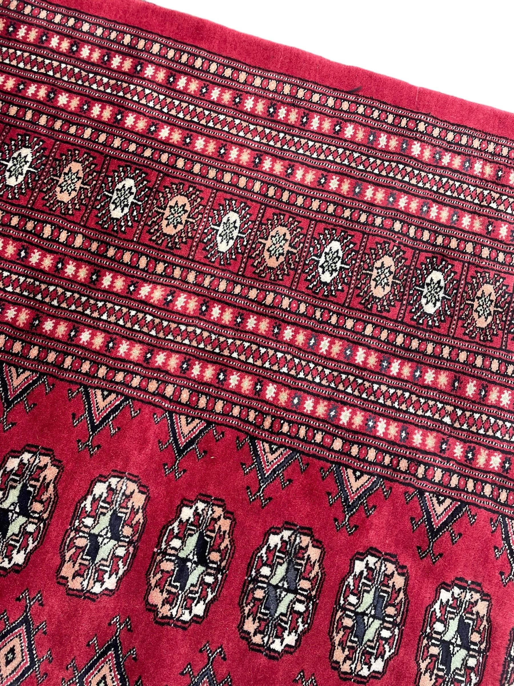 Persian Bokhara red ground carpet, decorated with six rows of traditional Gul motifs, multiple band border decorated with geometric patterns and motifs 