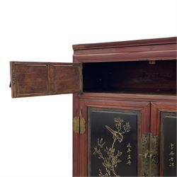 Late 19th century Chinese Qing dynasty red and black lacquered wood cabinet, Fujianese province, upper cupboard enclosed by two doors with relief carved and gilt panels depicting figures behind glass, the large cupboard enclosed by two panelled doors carved with trailing foliate branches and birds, inscribed with Chinese characters, to the left ‘Prolong life’ and to the right ‘Wealth and good fortune’, fitted with two drawers, square supports with carved brackets 