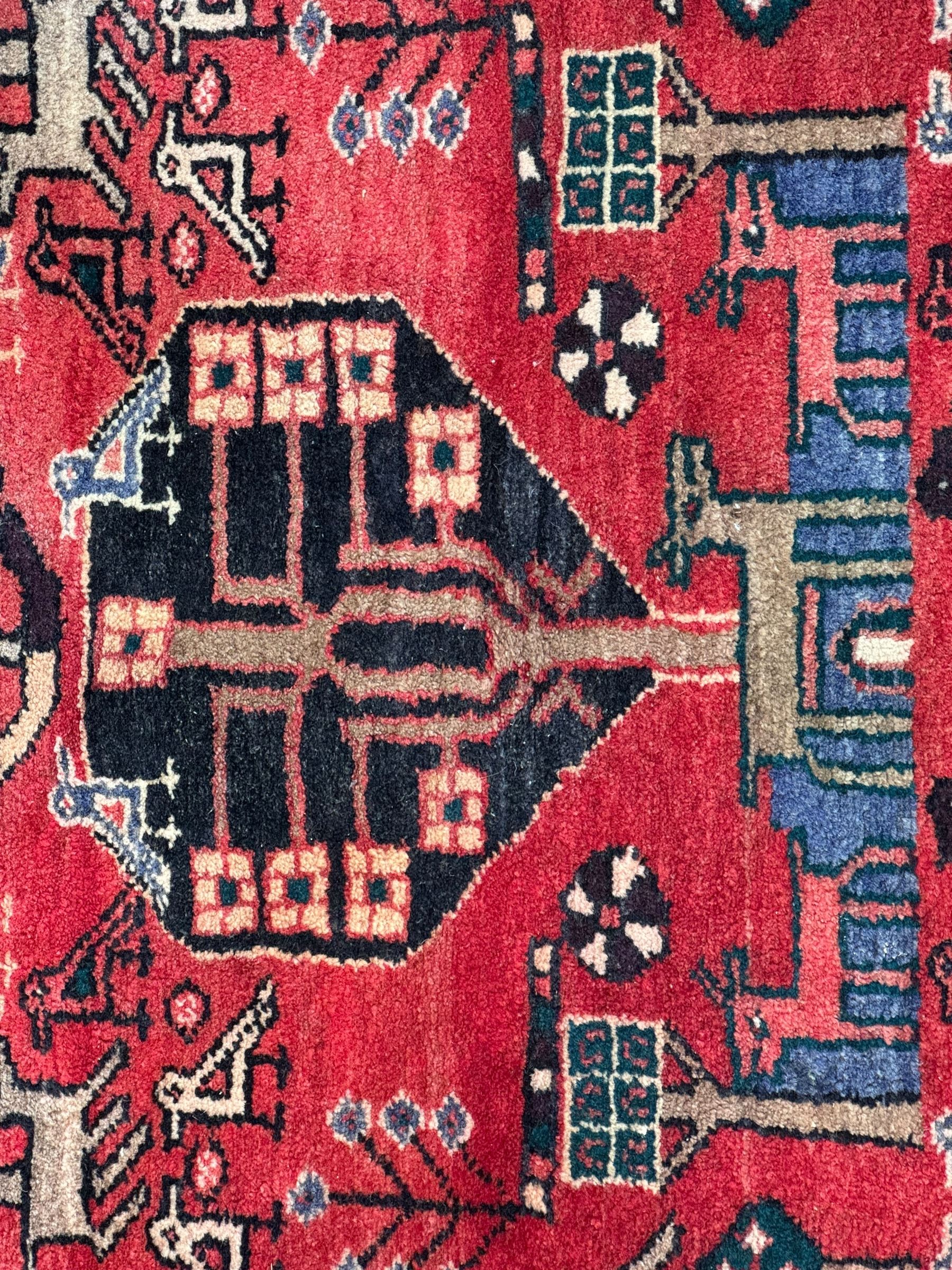 Persian crimson ground runner, the field decorated with stylised tree and animal motifs, indigo ground border decorated with alternating stylised flowerhead and bird motifs 