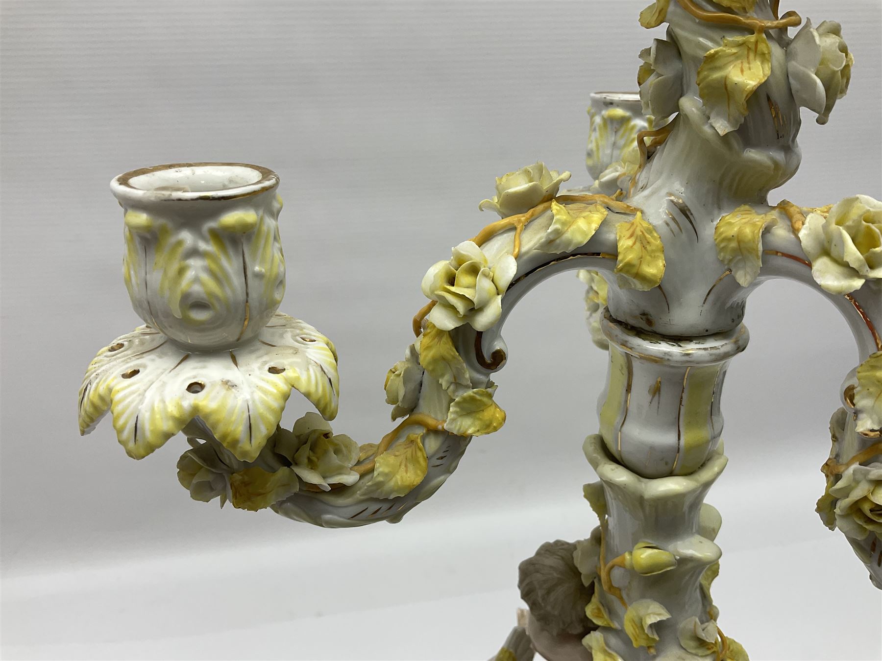 Dresden style candelabra, the central stem bordered by three branches, decorated with cherubs and yellow roses, H48cm