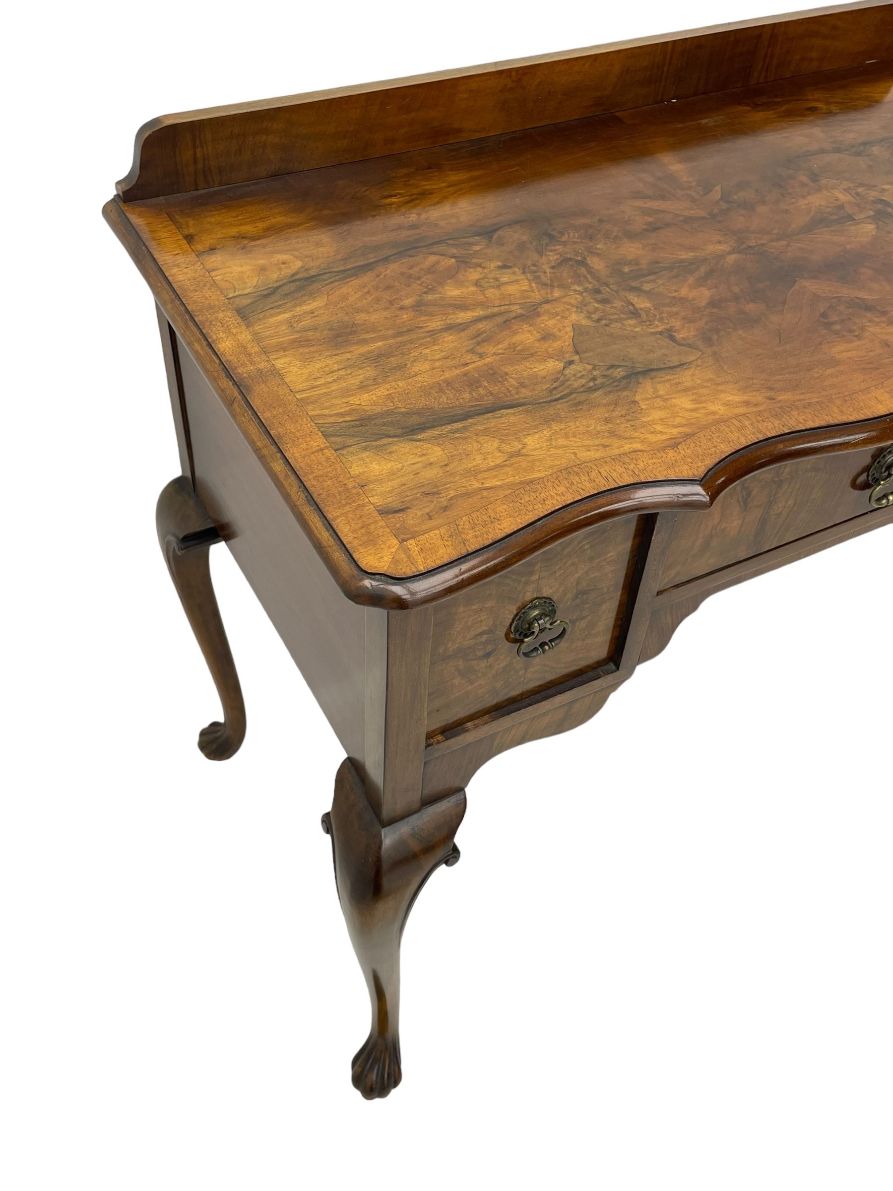 Mid-to-late 20th century figured walnut side table, raised back over figured top with cross banding and shaped front, fitted with three drawers, on cabriole supports with carved terminals 