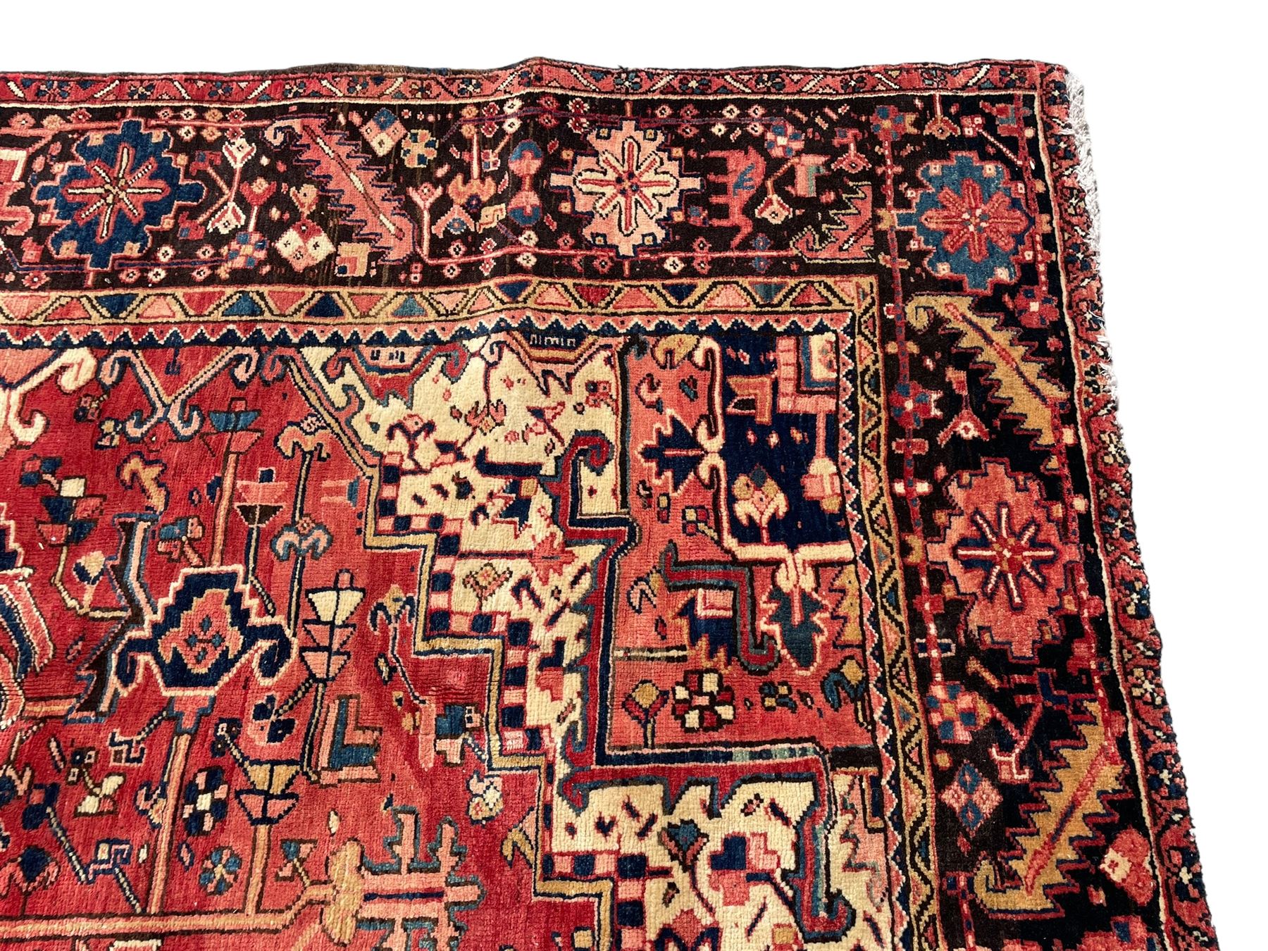 Persian Heriz red ground carpet, large central eight point medallion with projecting palmettes surrounded by small geometric motifs, decorated profusely with hooks, rosettes and animals, the busy border decorated with stylised foliate motifs within guard stripes 