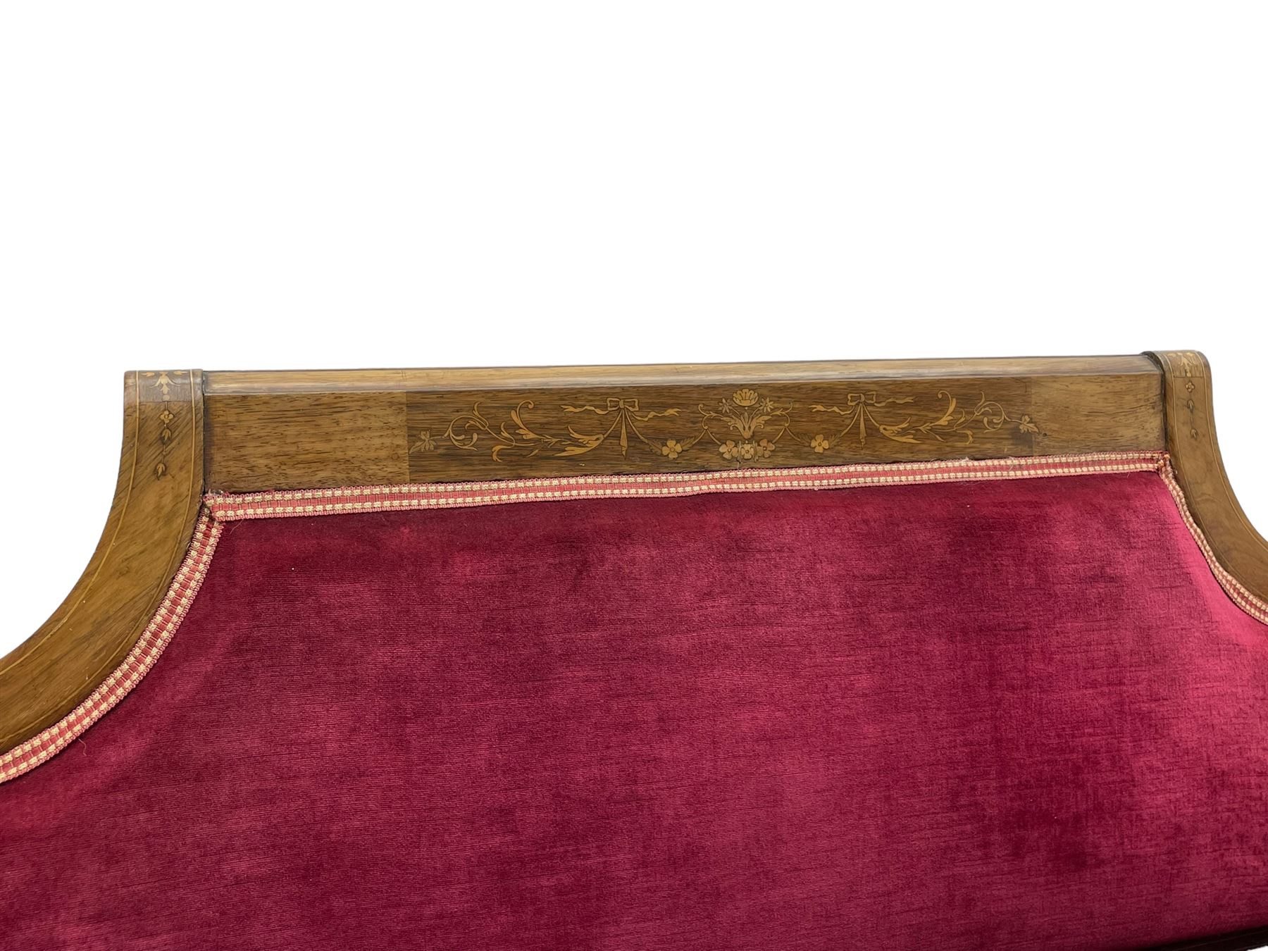 Late Victorian inlaid walnut two seat settee, the shaped cresting rail decorated with foliate inlays and boxwood stringing, upholstered in crimson velvet with sprung seat, raised on turned and fluted supports with ceramic castors