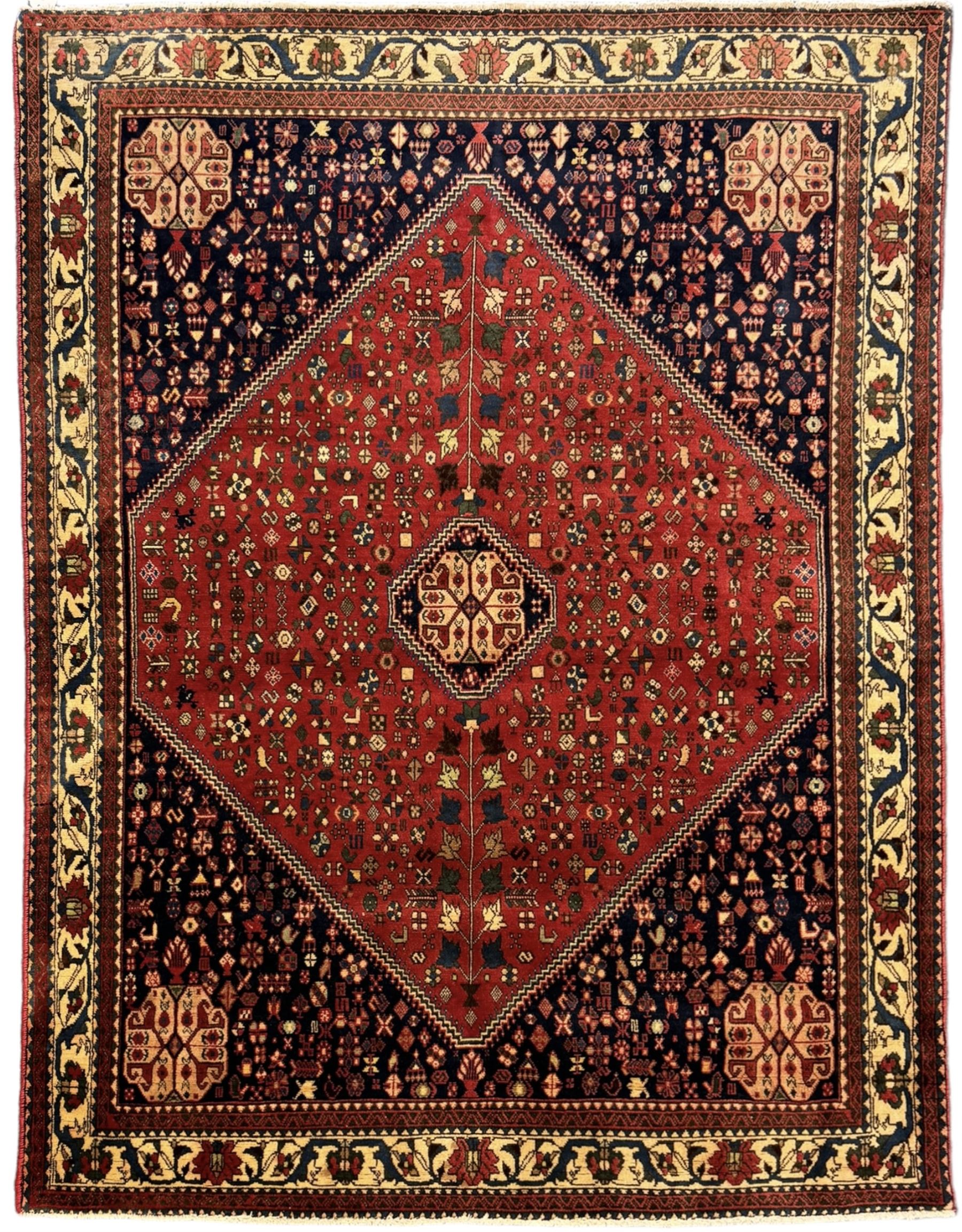 South West Persian Abadeh crimson ground rug, indigo ground with crimson lozenge field, decorated all over with small stylised motifs of flowerheads, hooks, animals and birds, guarded border decorated with trailing leaves and stylised plant motifs 