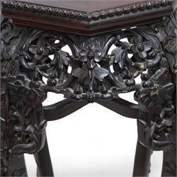 Early 20th century Chinese hardwood and marble top jardiniere or urn stand, octagonal top with central marble inset and bead edge, over pierced and carved foliate rails, the cabriole supports carved with trailing vines and protruding foliate decoration, united by X-stretcher on shaped claw feet