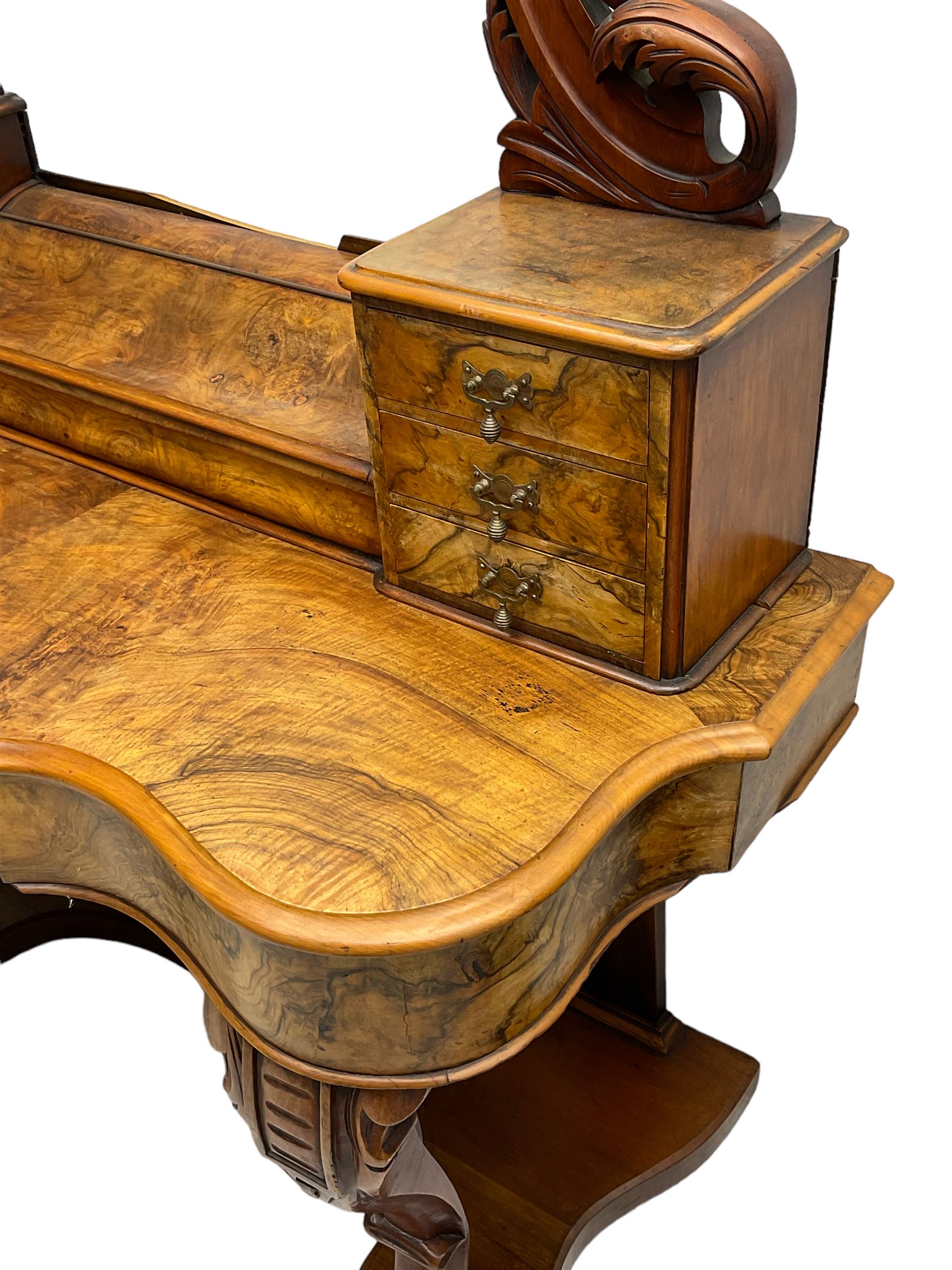 19th century figured walnut dressing table, the raised bevelled mirror back in carved foliage frame with scrolled terminals, fitted with central hinged compartment flanked by small trinket drawers, serpentine moulded top over single frieze drawer, on cabriole supports united by a platform base