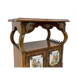 Mid-to-late 20th century French figured walnut three-tier bedside stand, shaped moulded top inlaid with figured book-matched veneers and crossbanding, double cupboard below enclosed by two doors mounted by painted porcelain panels depicting courting scenes within landscapes, on cabriole supports united by undertier, decorated with ornate cast metal cartouche mounts 