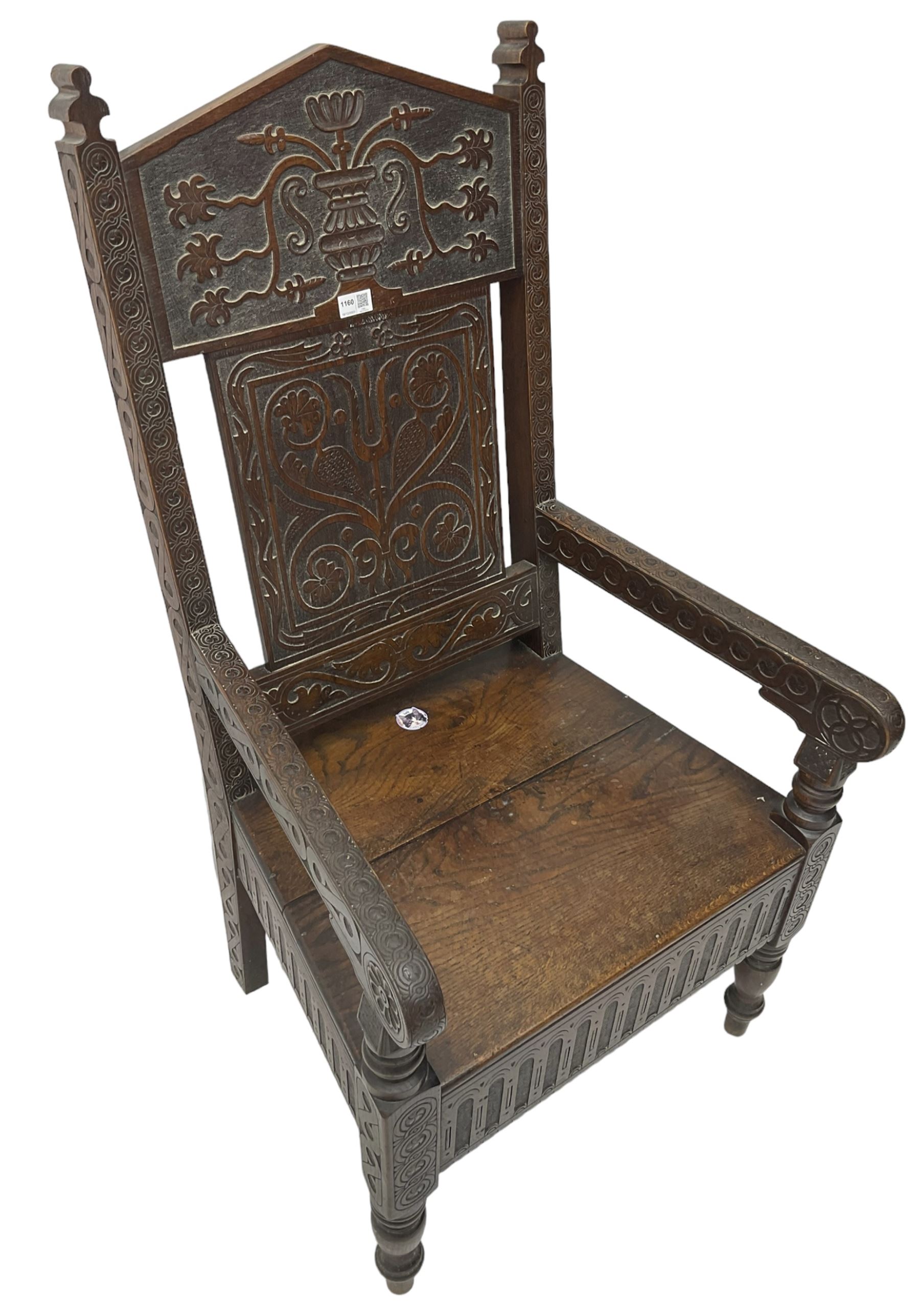 17th century design oak wainscot chair, the back profusely carved with scrolling foliate motifs, the arms carved with repeating guilloche decoration over an arcade apron and turned supports