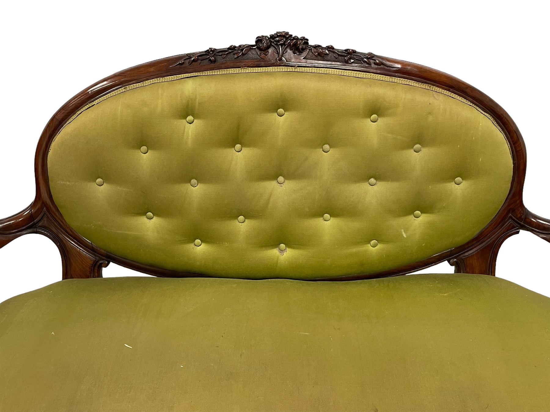 Victorian carved walnut framed two seat settee, cresting rail carved and moulded with a posy of roses and trailing foliate, over an oval back with scrolled arm terminals, serpentine fronted seat over cabriole supports with bell-flower carved knees, buttoned back and sprung seat upholstered in olive green fabric