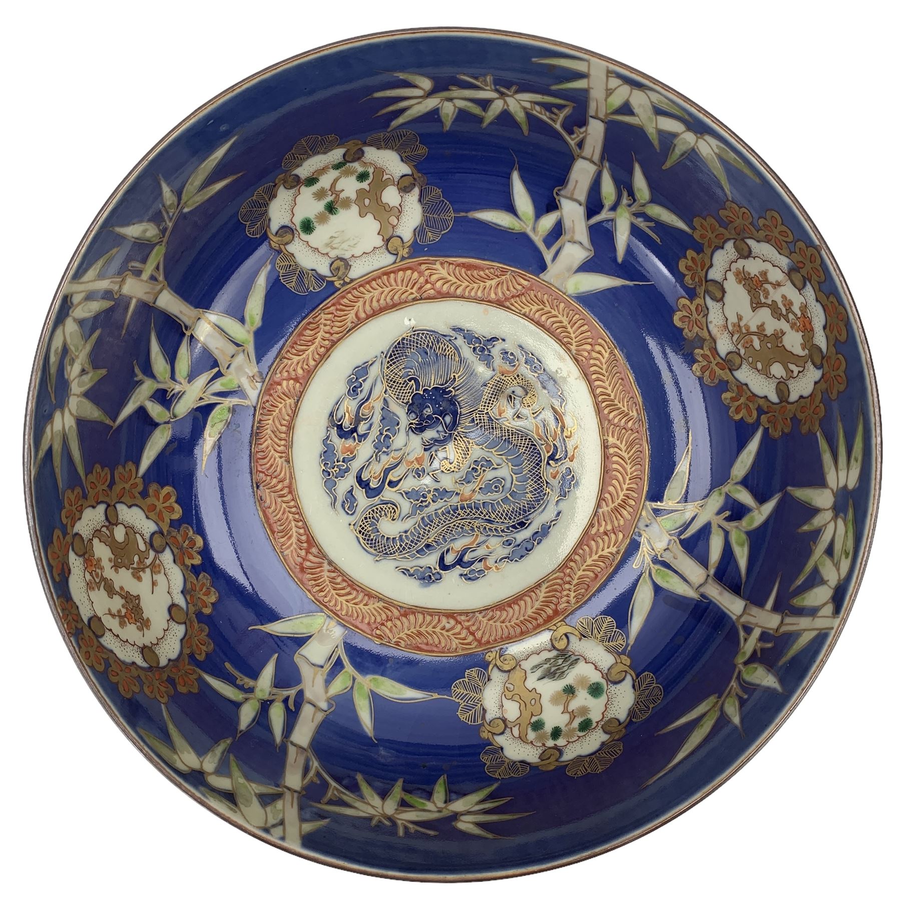 Set of four Japanese graduating porcelain bowls, each centrally painted with a coiled dragon in reserves, bamboo and foliate roundels against a blue ground, largest measuring D24.5cm (4)