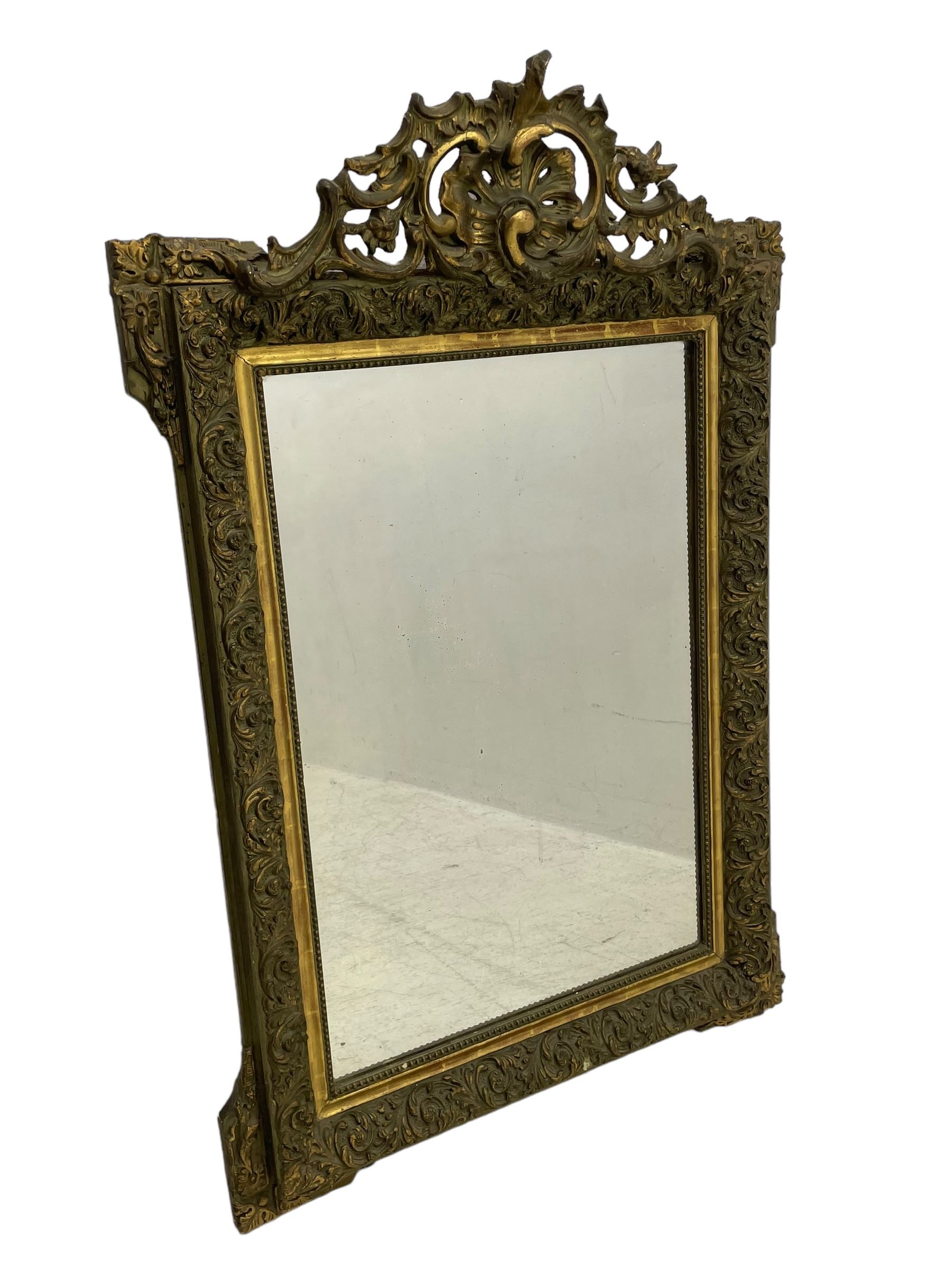 Victorian giltwood and gesso wall mirror, pierced shell cartouche pediment decorated with C-scrolls and curled leaves, moulded frame with curled acanthus leaf decoration and beaded inner slip, the corner brackets decorated with flower heads 