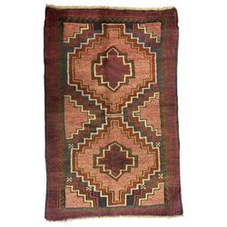 Baluchi crimson ground rug, the central field decorated with two stacked geometric lozenge medallions, surrounded by stepped multicoloured motifs, the wide border with alternating angular motifs in deep red, within a narrow brown guard stripe