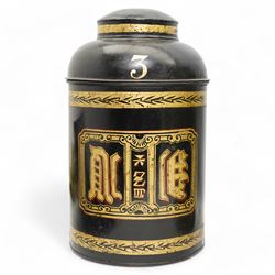 Two Victorian toleware shop display tea canisters, the first decorated in gilt with Chinese writing within laurel leaf borders and numbered 3, on black ground with hinged cover, H43cm, the second decorated in gilt with the number 8, within S scroll borders, on green ground, later converted to a table lamp, H81cm overall (2)